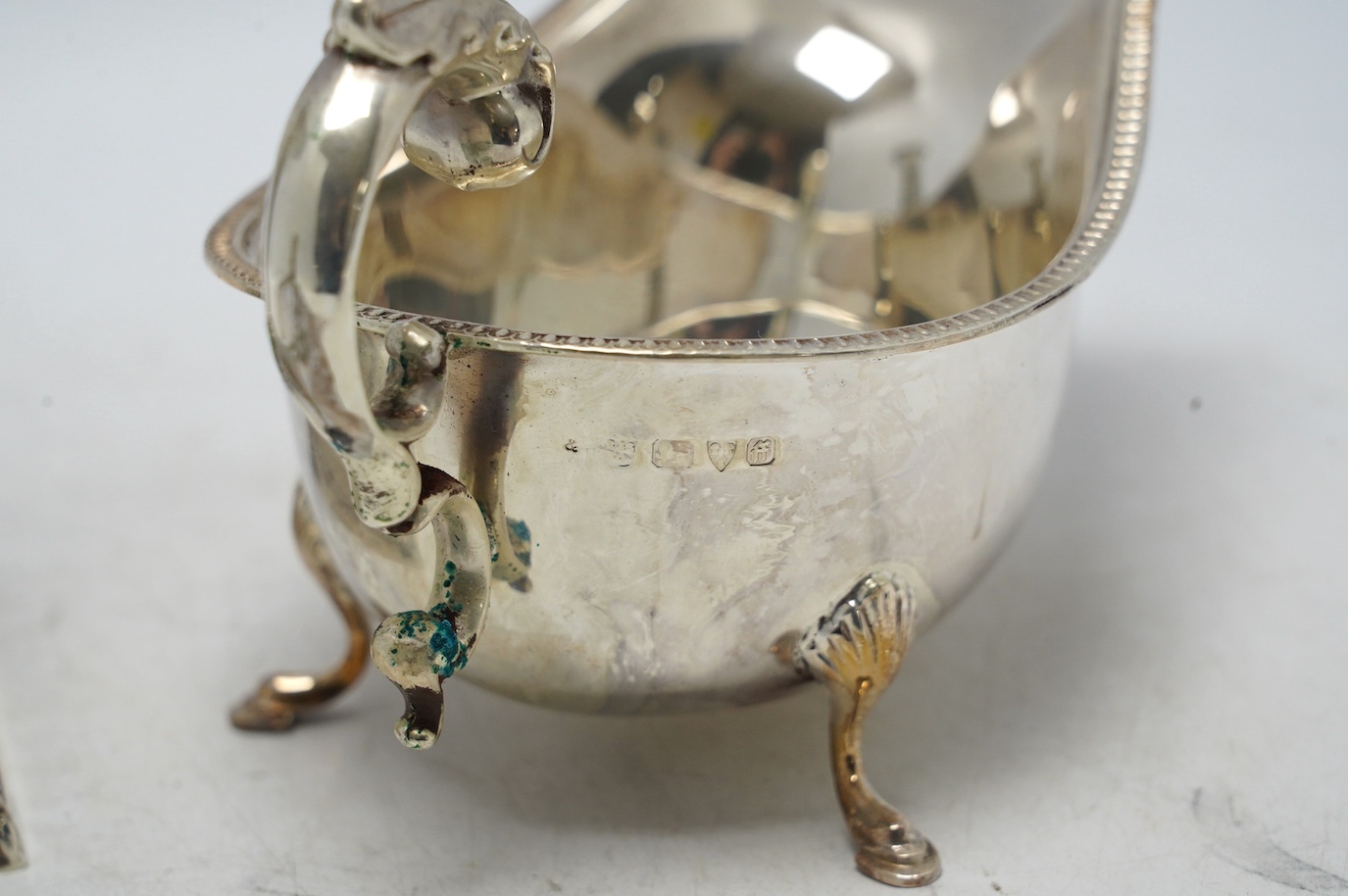 A late Victorian silver dwarf candlestick by Edward Hutton, London, 1893, 12.8cm, a silver sauceboat and three other items. Condition - fair